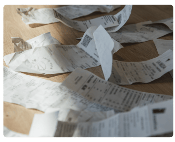 Mehrere Papierquittungen liegen verstreut auf einem Holztisch – Symbolbild für verlorene Belege im Ausgabenmanagement und die Notwendigkeit von Eigenbelegen.