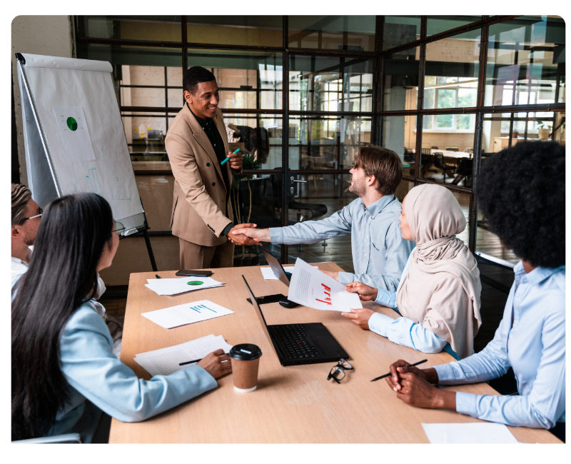 Teammeeting in einem modernen Büro – Führungskraft begrüßt Mitarbeitende mit Handschlag während einer Präsentation zu Ausgabenmanagement und Finanzprozessen