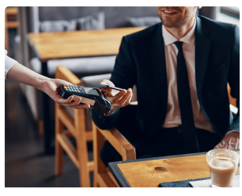 Mann auf Geschäftsreise bezahlt eine Mahlzeit mit der Mobilexpense-Firmenkreditkarte via Apple Wallet