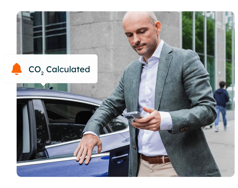 Mann steigt aus dem Auto und berechnet mit dem Handy den CO₂-Ausstoß für eine umweltbewusste und regelkonforme Kilometerabrechnung