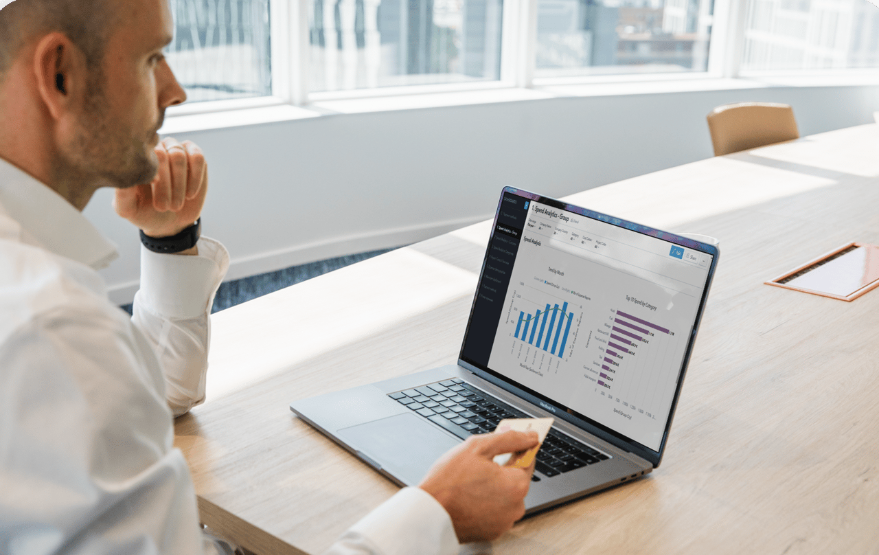 Man looking at analytics on screen holding a credit card.