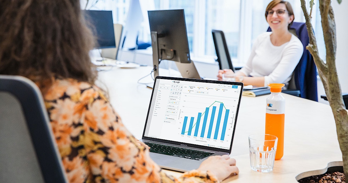 Woman sitting at conference table with laptop showing a graph.