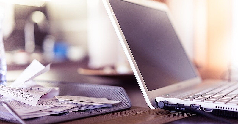 Open laptop with documents and receipts in inbox tray