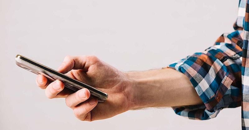 Hand holding phone tapping on screen.
